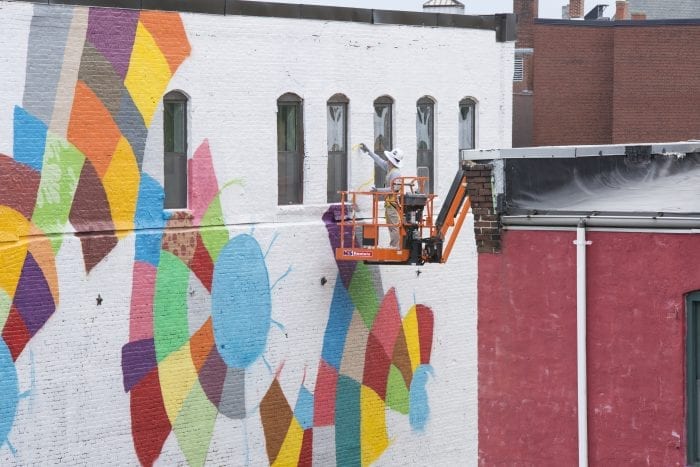 Cambridge native Caleb Neelon works on his mural on the side of 33 Munroe St. in Lynn on Friday during the Beyond Walls Mural Festival.