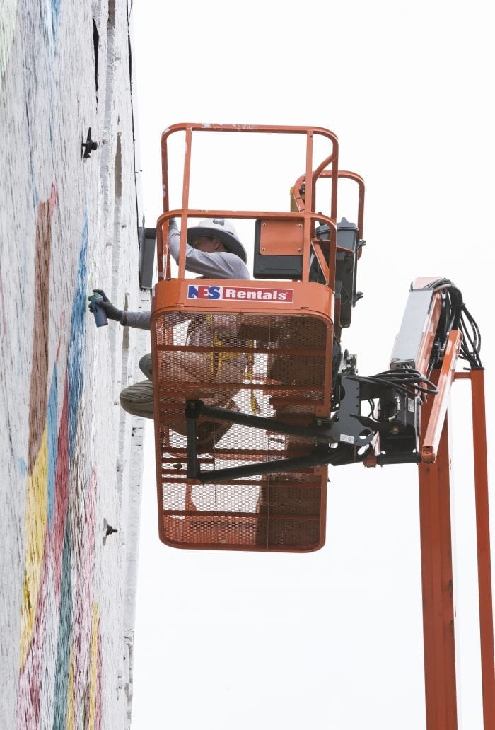Cambridge native Caleb Neelon works on his mural on the side of 33 Munroe St. in Lynn on Friday during the Beyond Walls Mural Festival.