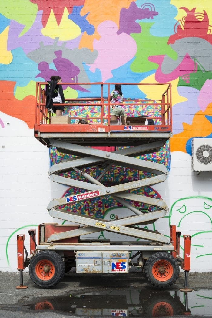 Vanessa Scrivani, left, and her sister, artist Miss Zukie, work on the mural at City Hall Square during the Beyond Walls Mural Festiavl on Friday.