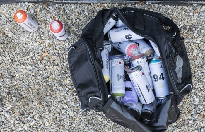 A bag filled with spray paint sits at the ready during the Beyond Walls Mural Festival in Lynn.