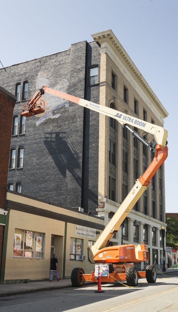 Artist Marka27 works on a face in his mural high above street level on Washington Street.