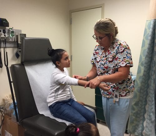 Lynn Community Health Center registered nurse Tammy Sands gives a child a flu shot.