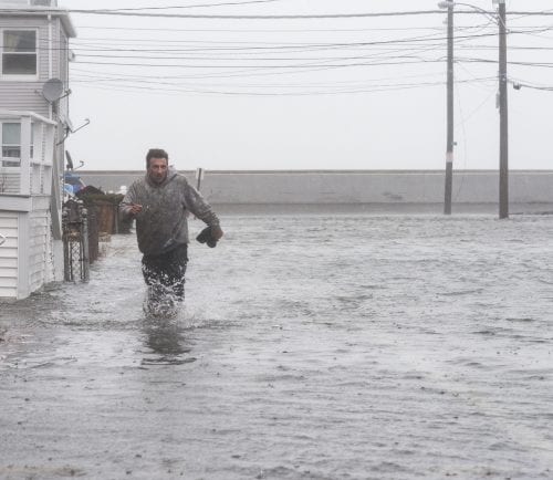 Nick Marazzi of East Boston wades through the flood waters on Pearl Avenue in Revere as he makes his way back to his truck.