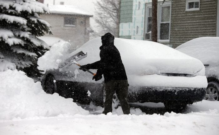Johnson Cano clears a path to his car at his Chestnut home during Tuesday’s storm.