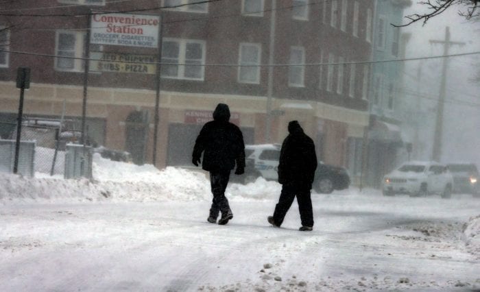 Lynn, MA—Tue March 13, 2018—A couple of pedestrians walk across Chestnut Street onto Union Street in Lynn during the snowstorm. There was very limited visibility when they were walking on the street.