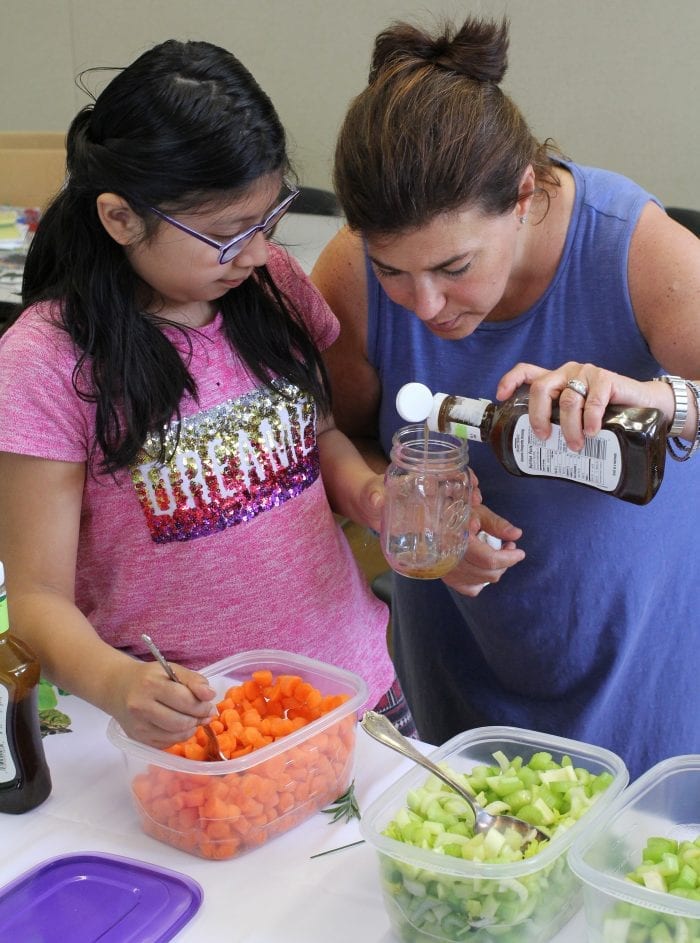 Lynn, Ma. 5-3-18. Hailley Mendez and Christine Meninno begin building a salad in a jar at Girl's Inc. with salad dressing.