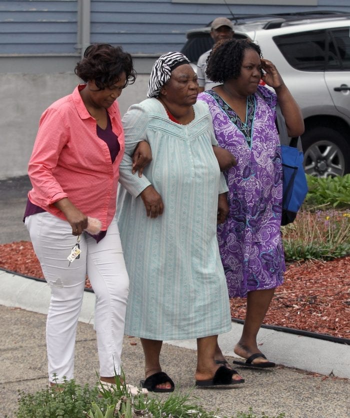 Lynn, MA--Fri May 4, 2018--Chrystell Exavier (in center of photo wearing cap), 89, was asleep in a second floor apartment when fire broke out at a two-family home at 15 Dorinda Circle shortly before 9 a.m. Friday morning. She is assisted near the fire scene by her friends Imene Mehu (at left in pink) and Navetar Brice (at right, in purple) Chrystell was once Navetar's baby sitter.