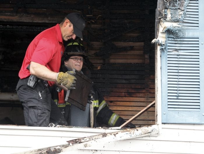 State Police fire investigator Mike Sweet (red shirt, left) and Lynn fire investigator Lt. Mike Smith (in uniform, right) comb through debris at a two-alarm fire at a two-family home at 15 Dorinda Circle that broke out shortly before 9 a.m. Friday morning.